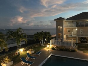 Um hotel na praia com piscina, espreguiçadeiras e vista para o oceano.