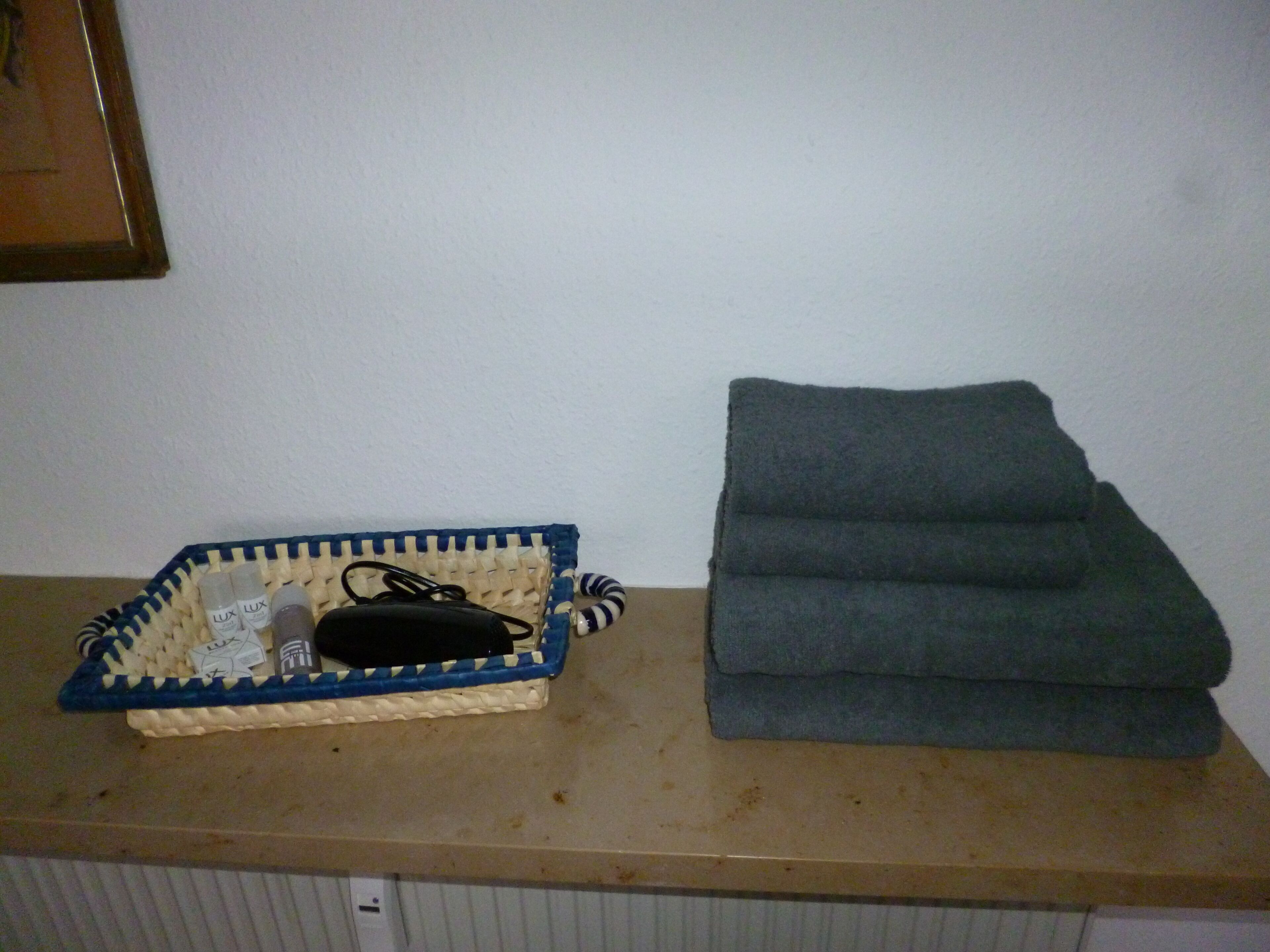 A woven basket with toiletries and a folded grey towel on a countertop.