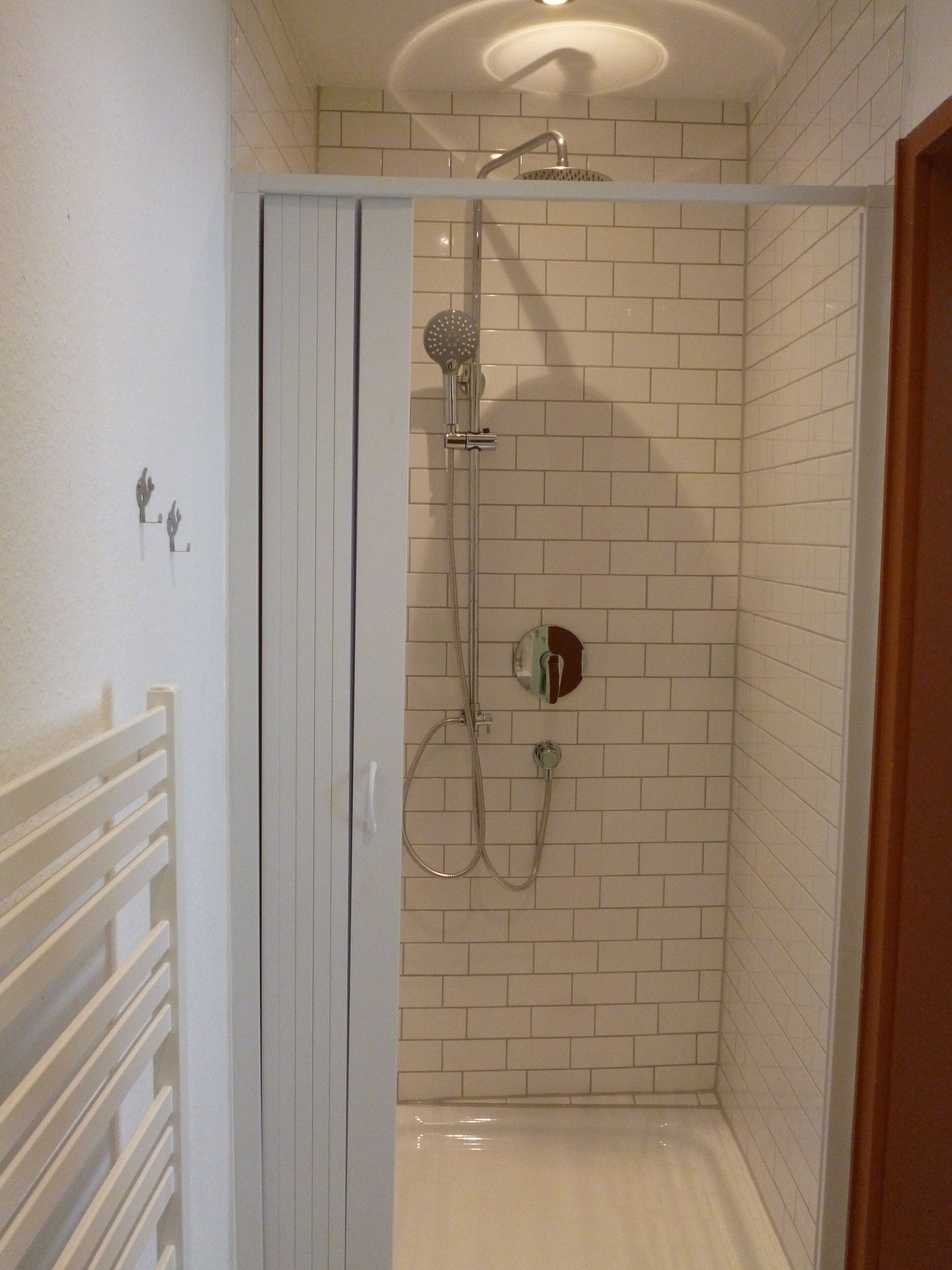A shower with a handheld showerhead and a wall-mounted faucet.