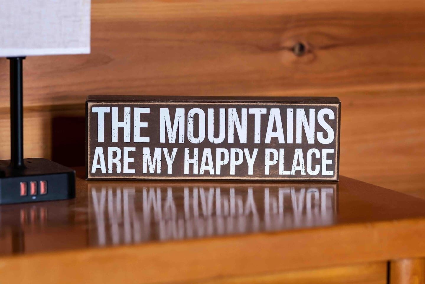 A wooden table with a sign that reads "THE MOUNTAINS ARE MY HAPPY PLACE."