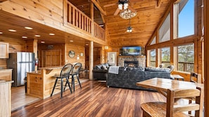 Ein Holzblockhaus-Interieur mit Küche, Essbereich und Wohnzimmer, mit Holzböden, Kamin und großen Fenstern.