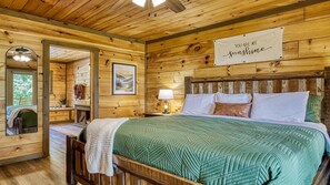 Une chambre à coucher dans une cabane en bois, avec un lit, une table de chevet, une lampe, un miroir et un panneau accroché au mur.