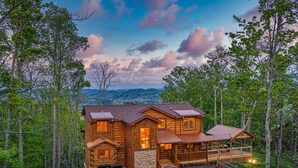 Une cabane en rondins avec des fondations en pierre, plusieurs terrasses et une vue imprenable sur les montagnes.