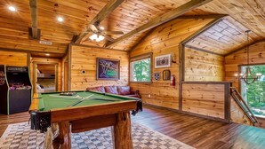 Un intérieur en bois agrémenté d’une table de billard, d’un jeu de fléchettes et d’un tableau représentant un joueur de billard hors pair.