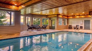 An indoor swimming pool with a wooden ceiling, large windows, and outdoor seating. - The Appalachian- Mtn Views, Private/ Heated Indoor Pool, Game Room, Hot tub (Sevierville)