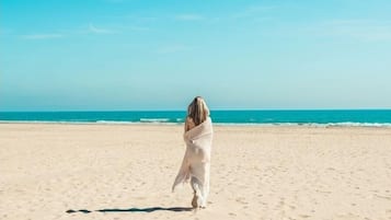 Vlak bij het strand, wit zand, parasols, yoga op het strand