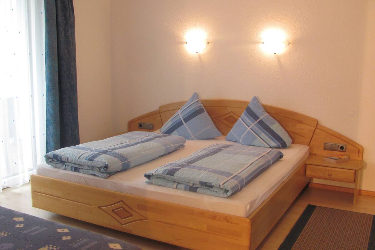 Una cama de madera con cabecera, dos mesitas de noche y un tocador.