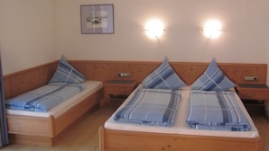 Uma cama de casal com cabeceira de madeira e duas mesas de cabeceira, cada uma com uma luminária.