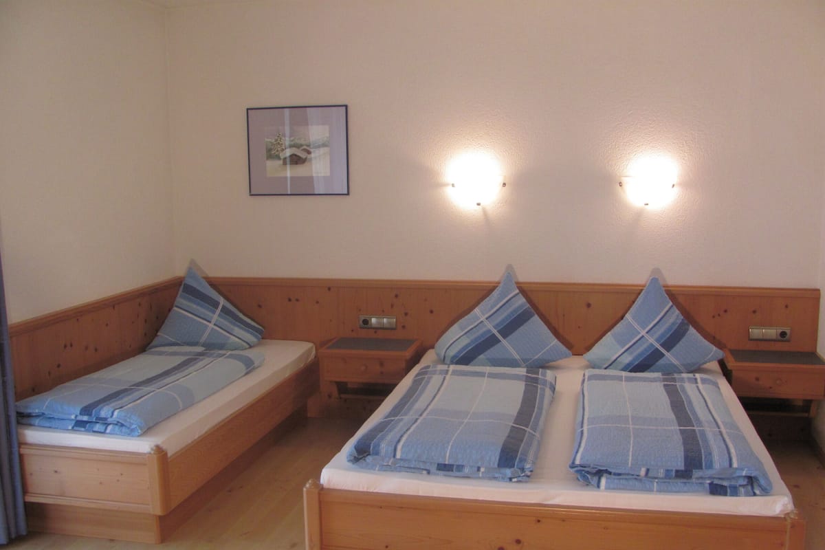 Una cama doble con cabecera de madera y dos mesitas de noche, cada una con una lámpara.