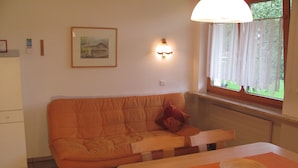 Um quarto pequeno e aconchegante com um sofá, uma mesa e uma janela.