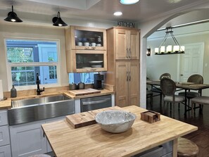 A modern kitchen with wooden cabinets, a stainless steel sink, and a wooden island with a bowl. - Walnut Creek  3 bedrooms - 2 Full Bathrooms. (Walnut Creek)