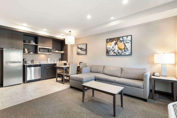 A modern living room with a grey sofa, a coffee table, and a dining area with a table and chairs.