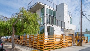 Ein modernes, zweistöckiges Gebäude mit Balkon, großen Fenstern und einem Holzzaun.