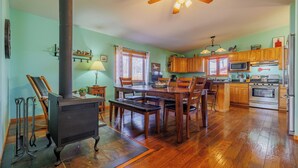 A kitchen with wooden cabinets, a stove, and a dining area with chairs and a table.