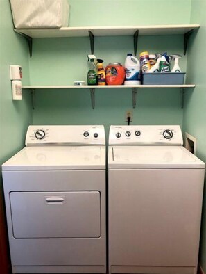 Convenient laundry facilities with two front-loading washing machines and storage for cleaning supplies.