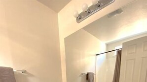 Un baño con inodoro blanco, lavabo con espejo y armarios de madera.