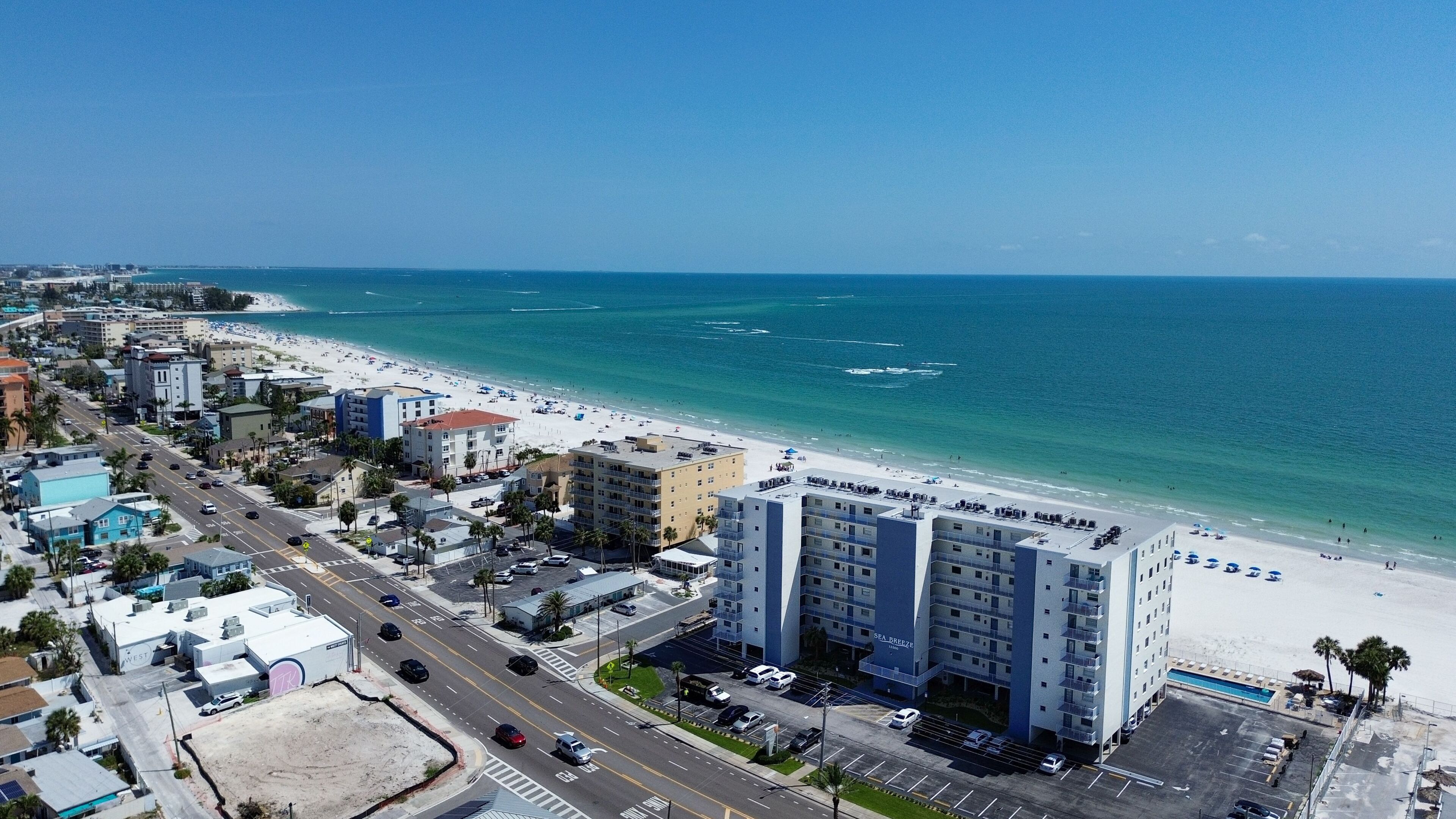 Un hôtel situé sur la côte, avec plusieurs étages, un parking et une vue sur la plage.