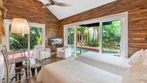 Ein geräumiges Schlafzimmer mit einem großen Bett, einem Deckenventilator und Blick auf einen Swimmingpool.