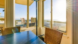 A room with a large window overlooking a beach, a table, and two wicker chairs. - Unobstructed View Of Monterey Bay! (Aptos)