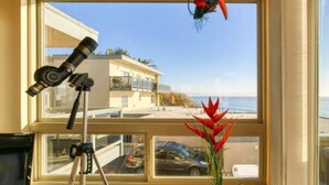A room with a telescope, a potted plant, and a view of the ocean and buildings. - Unobstructed View Of Monterey Bay! (Aptos)