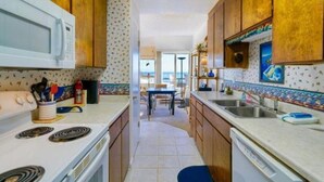 A kitchen with wooden cabinets, a microwave, stove, and a dining area with a view. - Unobstructed View Of Monterey Bay! (Aptos)