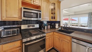 Una cucina moderna con mobili in legno, elettrodomestici in acciaio inossidabile e vista sull'oceano.