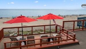 Una veranda sulla spiaggia con ombrelloni rossi, posti a sedere all'aperto e vista sull'oceano.