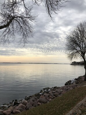 Une vue sur le lac, avec une rive rocheuse, un arbre et un horizon lointain.