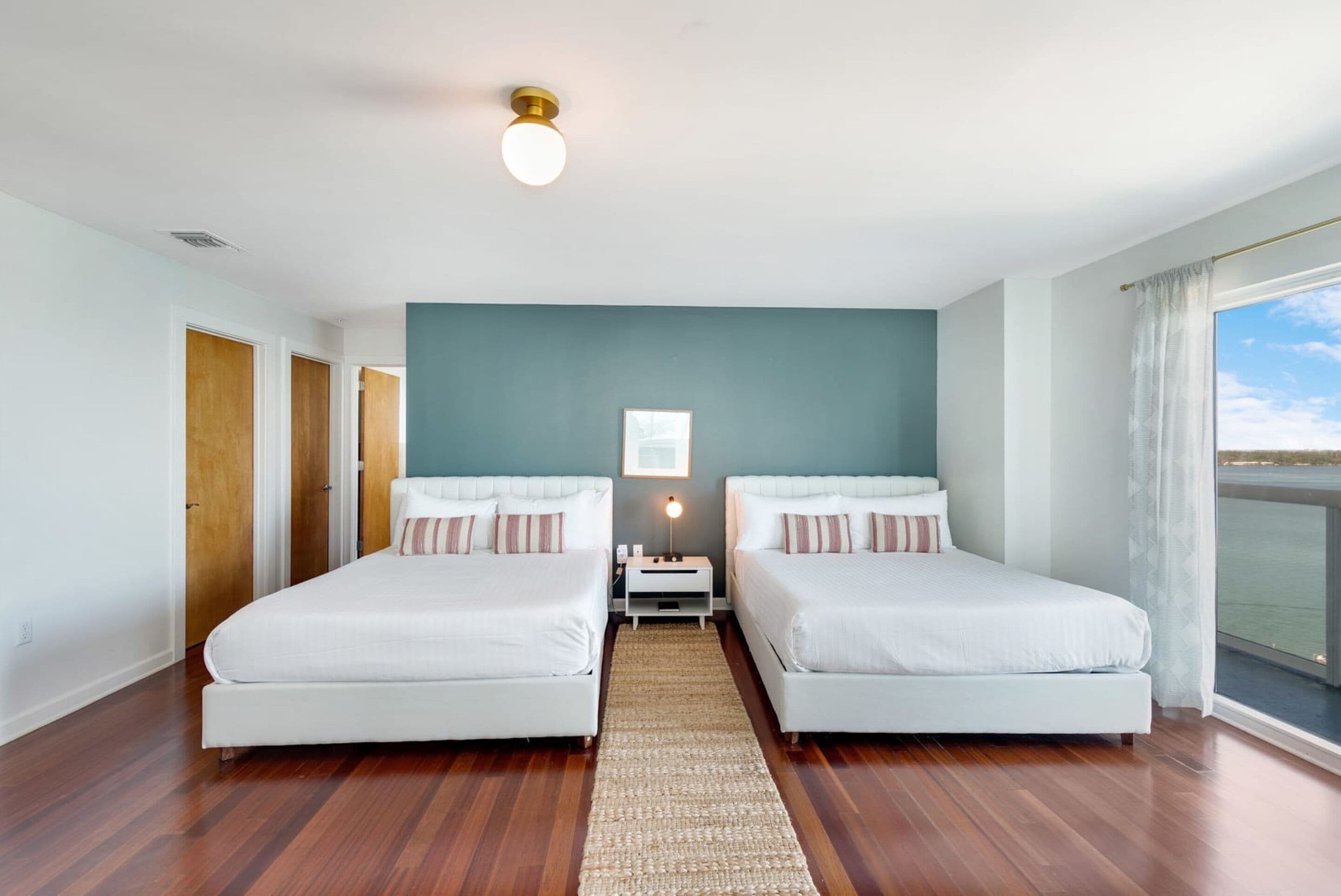 A hotel room with two beds, a view of the sea, and a large window.
