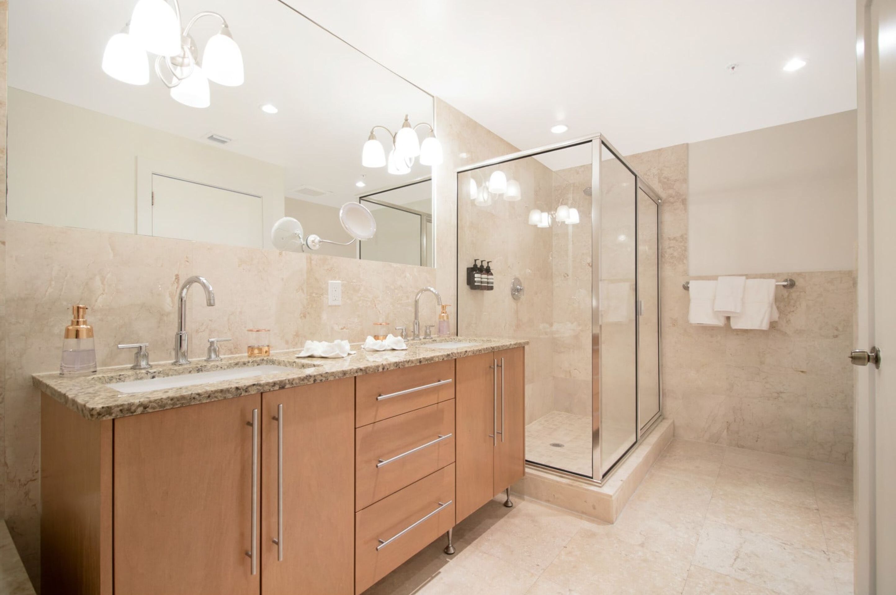 A modern bathroom with a large vanity, a glass-enclosed shower, and a large mirror.