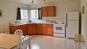 Une cuisine de taille réduite, avec des meubles de rangement en bois, un réfrigérateur blanc, un four à micro-ondes et une cuisinière.