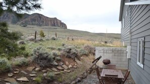 Une terrasse avec une table et des chaises, un mur en pierre et une montagne en arrière-plan.