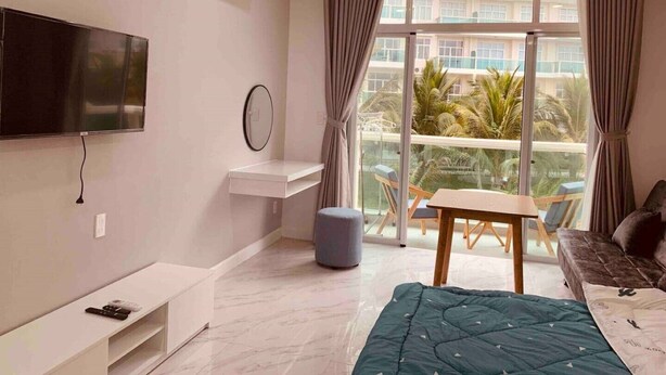 Una habitación de hotel moderna con un ventanal grande, un televisor de pantalla plana, una cama, una mesita y un sofá.