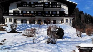 Un edificio grande de dos pisos con un balcón en el piso superior, rodeado de nieve.