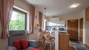 Un espacio habitable compacto con sofá, mesa de comedor, sillas, kitchenette y pequeña zona de cocina.
