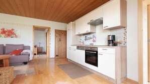 A modern kitchen with white cabinets, a built-in oven, and a coffee maker. - Vacation apartment with south-facing balcony (Riedering)
