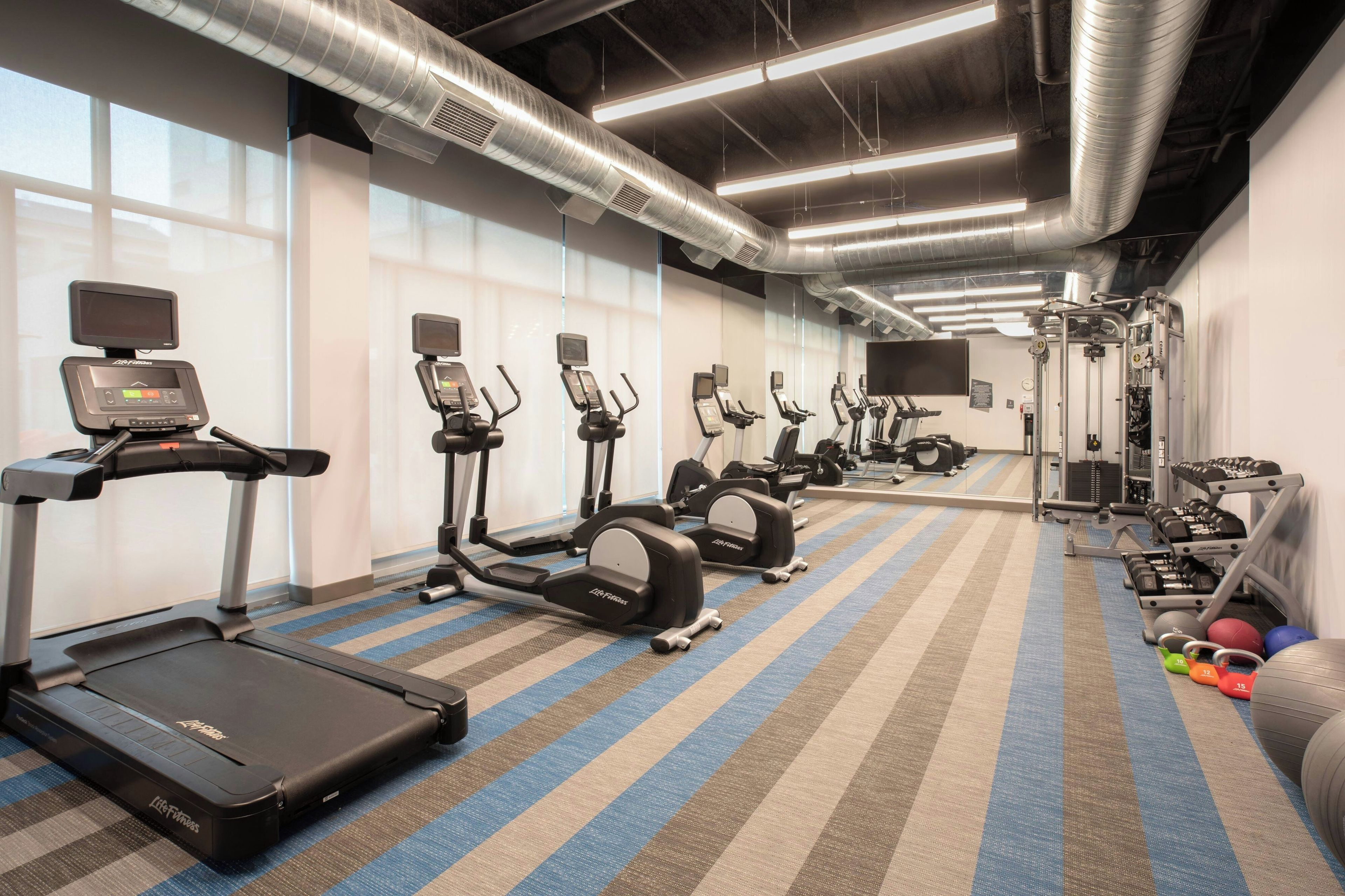 A gym with treadmills, elliptical machines, and free weights.