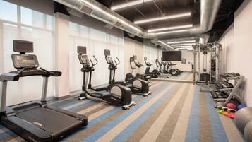 A gym with treadmills, elliptical machines, and free weights.
