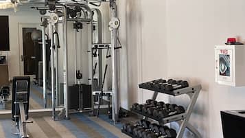 A gym with exercise equipment, a dumbbell rack, and a wall-mounted AED box.
