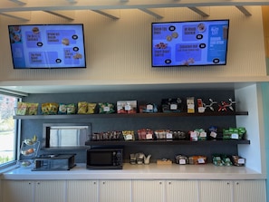 A breakfast bar with a menu display, snack and coffee options, and a microwave. - Aloft by Marriott Omaha Aksarben Village (Omaha)