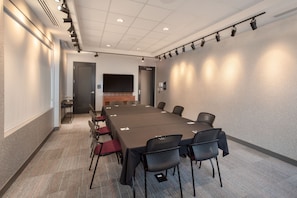 A conference room with a long table, chairs, a flat-screen TV, and a carpeted floor. - Aloft by Marriott Omaha Aksarben Village (Omaha)