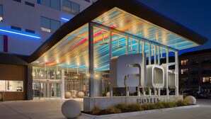 A modern hotel entrance with a glass facade, a prominent 'HOTEL' sign, and a well-lit outdoor area. - Aloft by Marriott Omaha Aksarben Village (Omaha)
