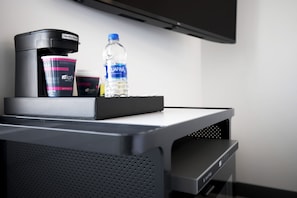 A coffee machine, a water bottle, and a cup on a table in a hotel room. - Aloft by Marriott Omaha Aksarben Village (Omaha)