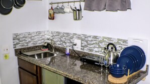 Eine kompakte Küche mit Granit Arbeitsplatte, Edelstahlspüle und eingebautem Backofen.