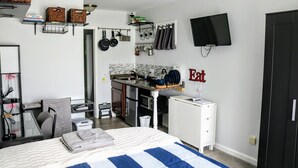 Ein kleines Schlafzimmer mit einem Bett, einem Schreibtisch und einer Küchenzeile.