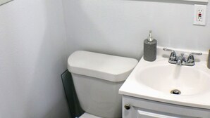 Ein kleines, sauberes Badezimmer mit Toilette, Waschbecken und einem Spiegel darüber.