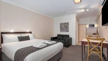 A hotel room with a bed, a desk, a chair, a sofa, and a TV.