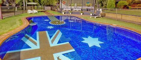 Una piscina al aire libre, sombrillas, sillones reclinables de piscina