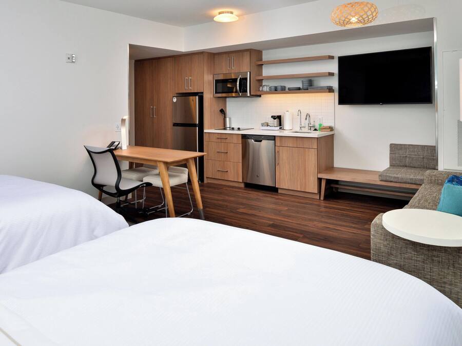 A compact hotel room with a kitchenette, a dining area, and a seating space.