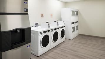 Un cuarto de lavandería con dispensador de agua, varias lavadoras y secadoras.